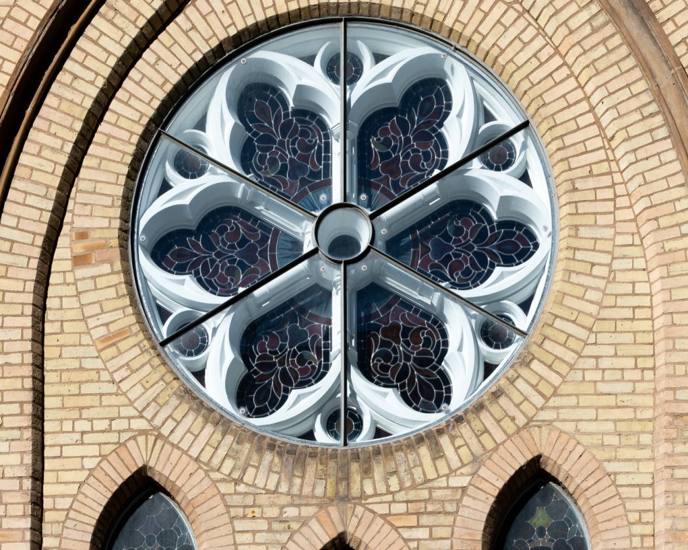 Stainglass and stone window on church exterior.