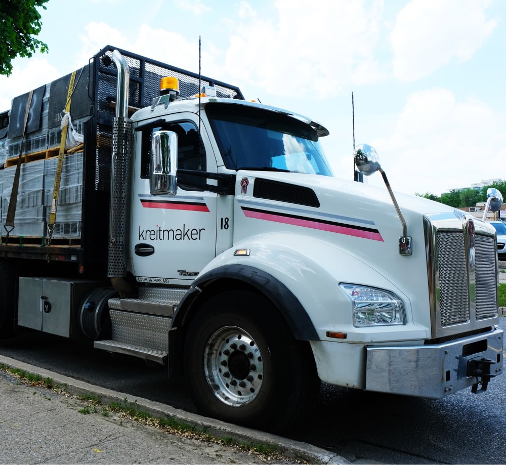 Grey concrete truck with kreitmaker logo on side.