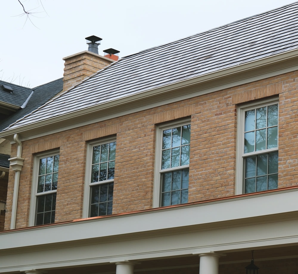 Two story beige brick house with a large patio overhang.