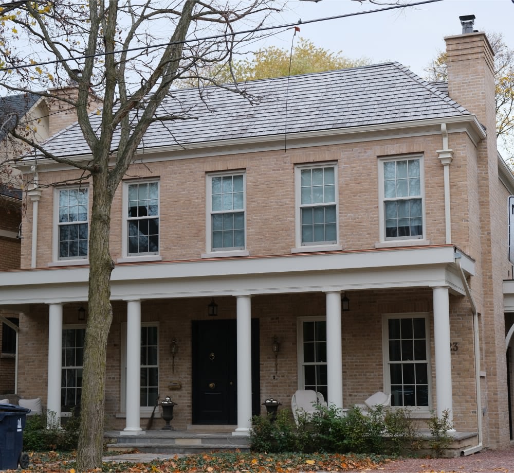 Two story beige brick house with a large patio overhang.