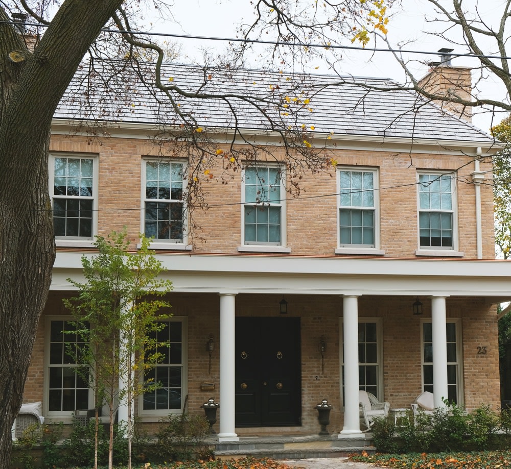 Two story beige brick house with a large patio overhang.