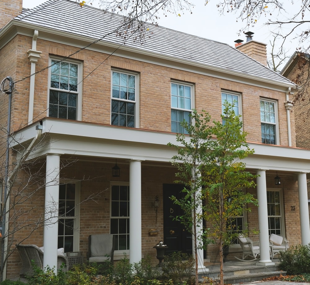 Two story beige brick house with a large patio overhang.