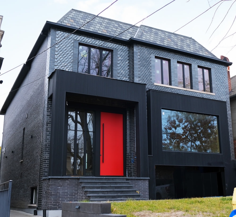 Residential home with black glazed brick and red door.