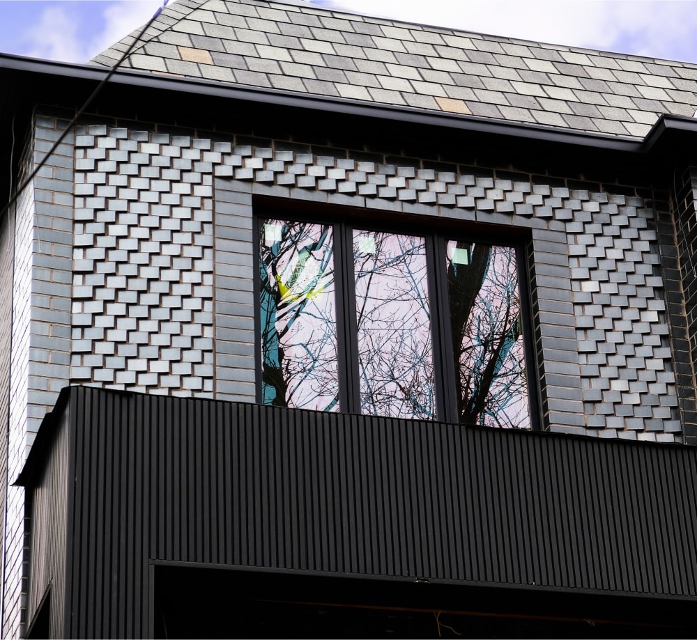 Exterior of house with black glazed brick and a window.