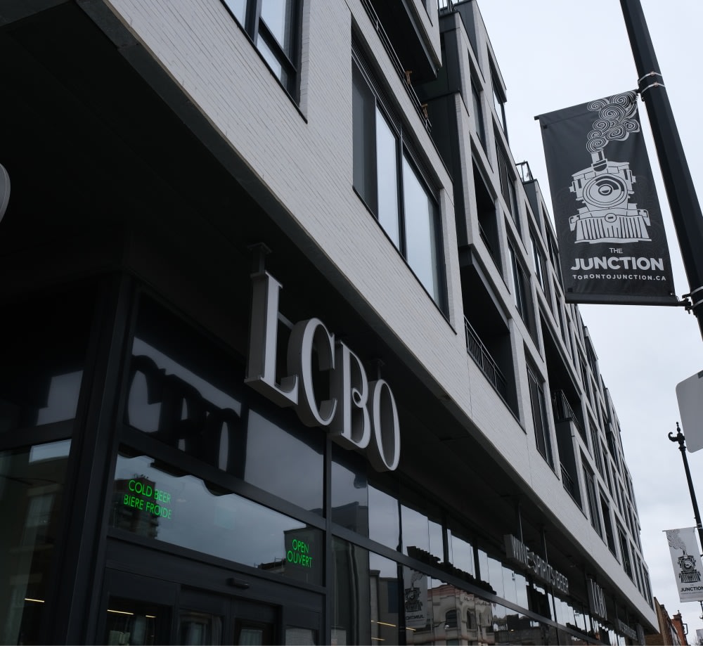 LCBO sign hanging on building with grey brick.