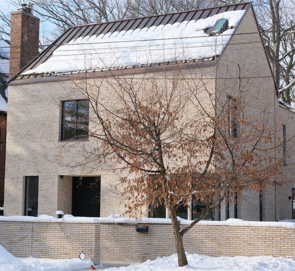 Exterior of beige brick house with snow.