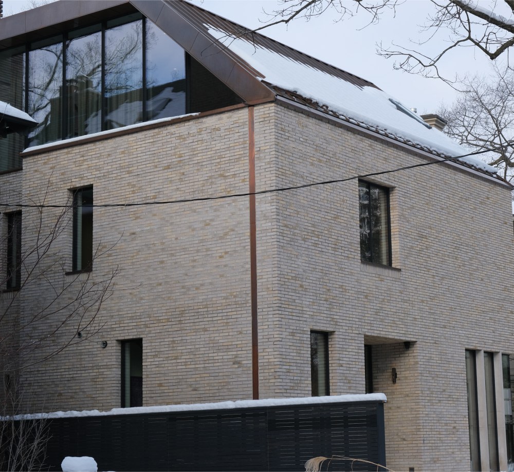 Exterior corner of house with beige brick and metallic detail.