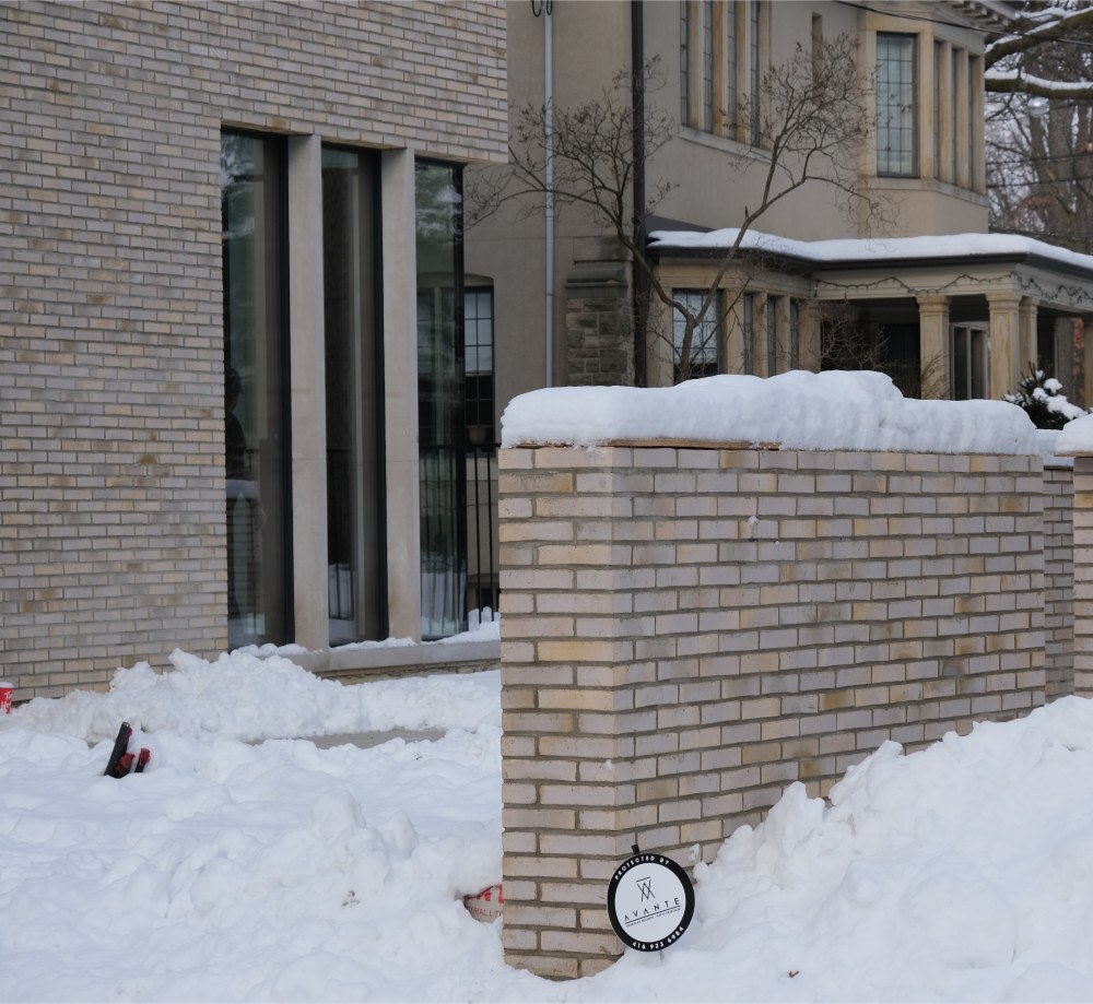 Decorative half wall with beige brick covered in snow.