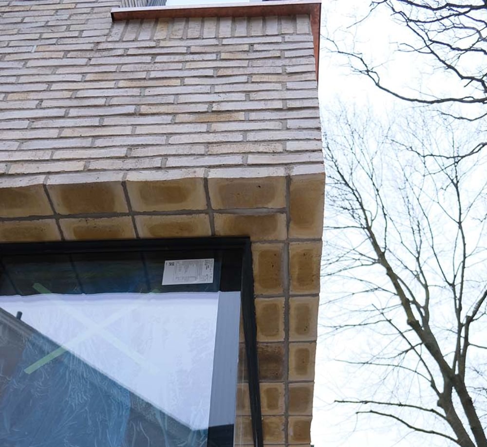 Exterior corner detailing on a house with beige brick.