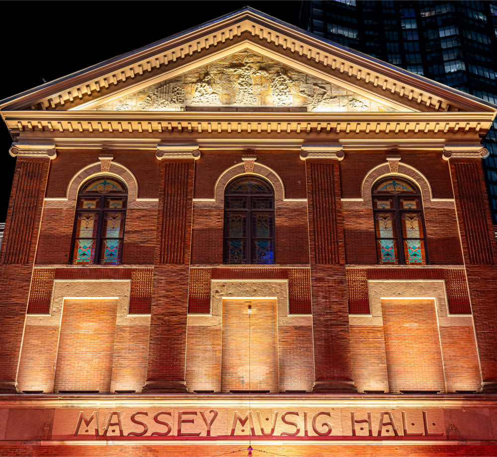 Front of Massey Hall lit up at night with lights.