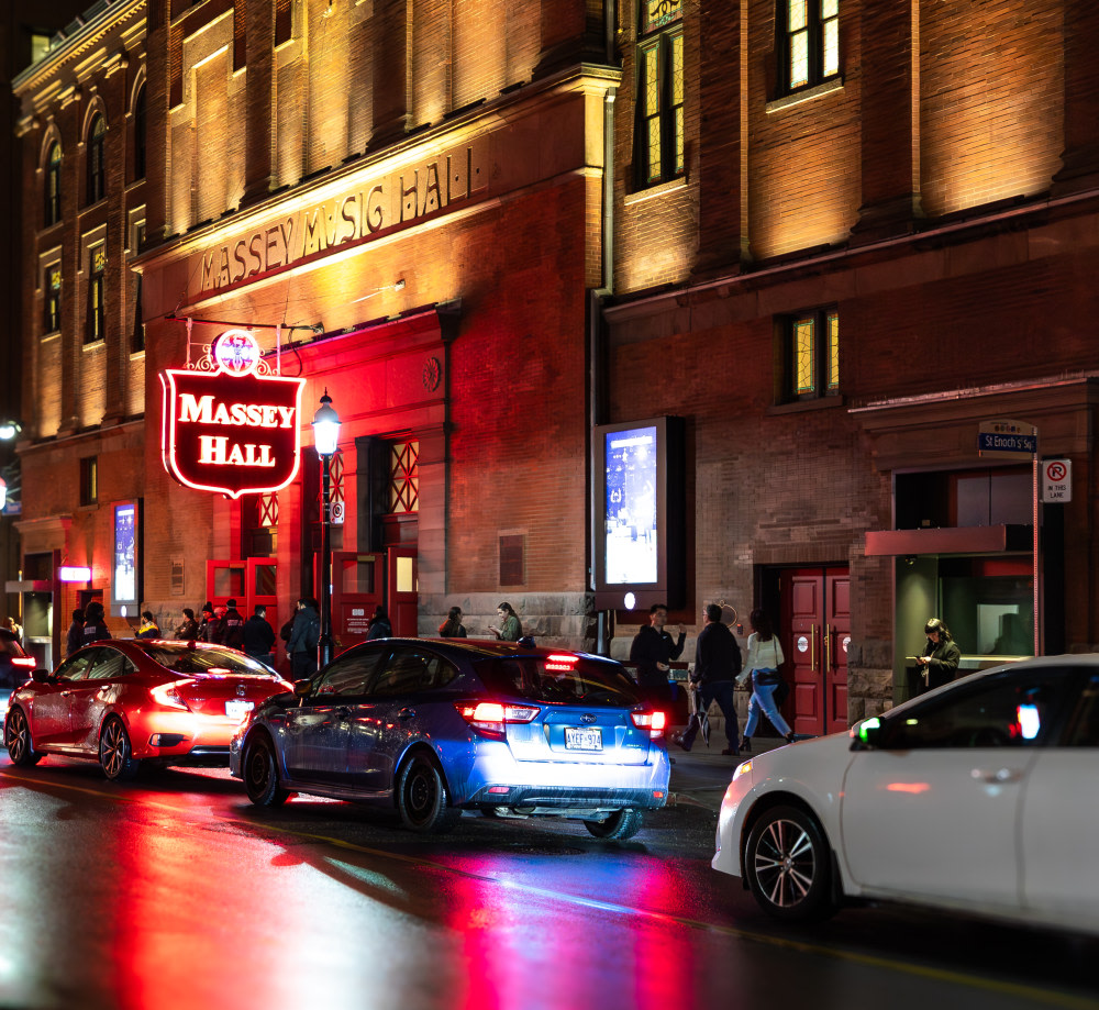 Massey Hall sign and building lit up at night.