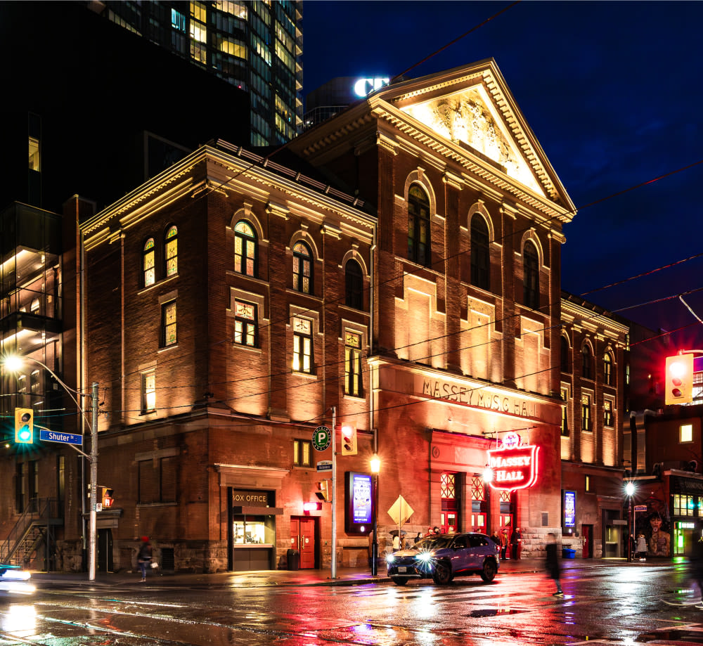 Angled view of Massey Hall lit up at night with lights.