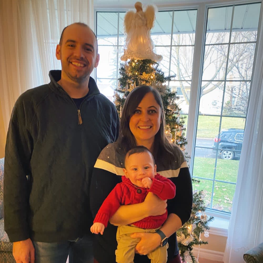 mom, dad, baby boy in front of Christmas tree