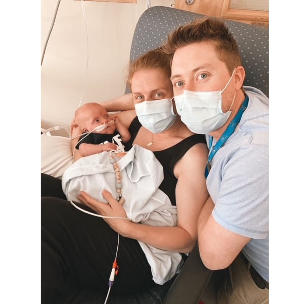 Mom and dad with masks with newborn in hospital.