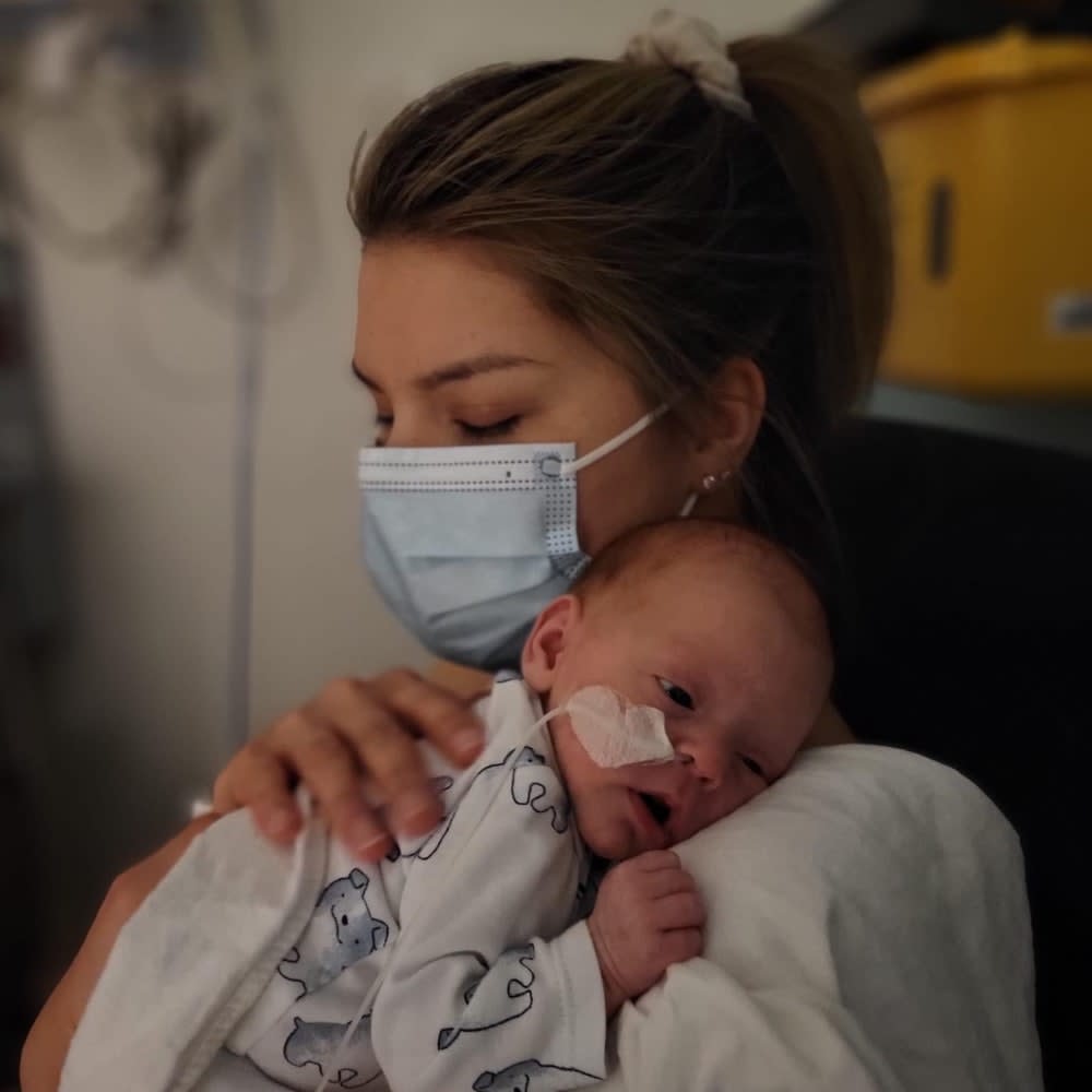 Mom with face mask hold new born baby in hospital