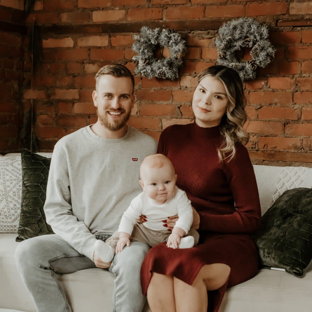 Mom and dad holding baby boy on couch.