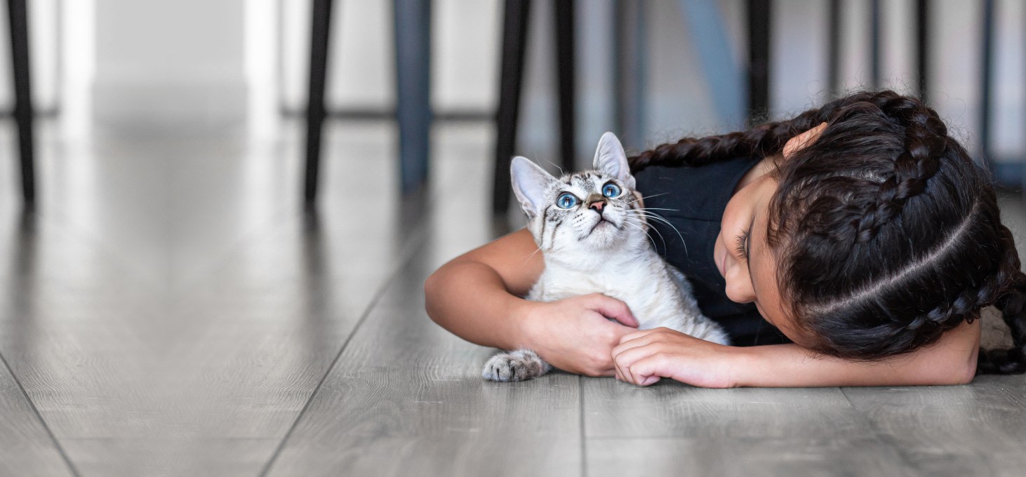 Child and cat laying on the floor together.