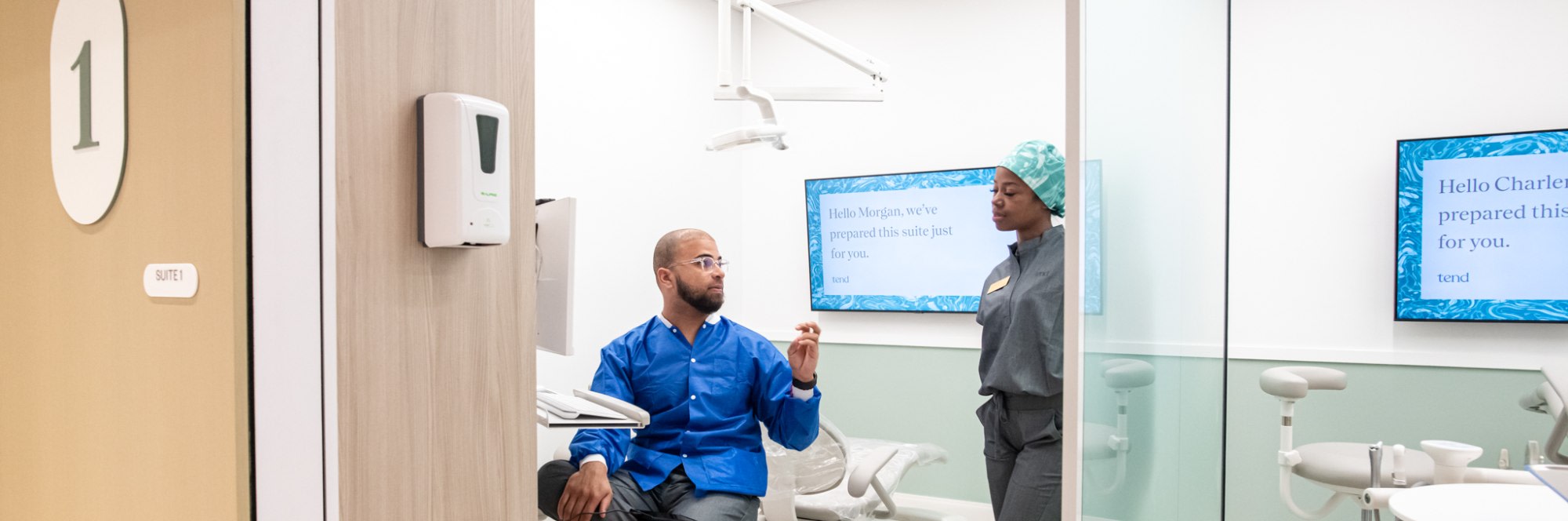Two team members chat in a dental exam room.