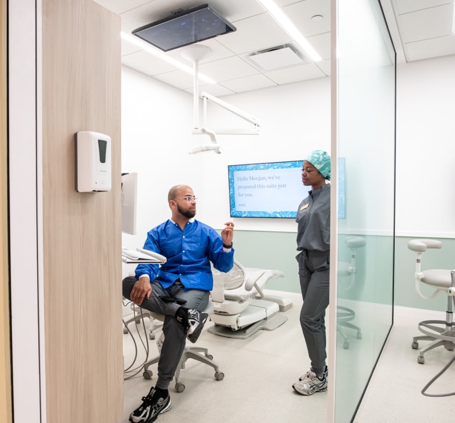Two team members chat in a dental exam room.