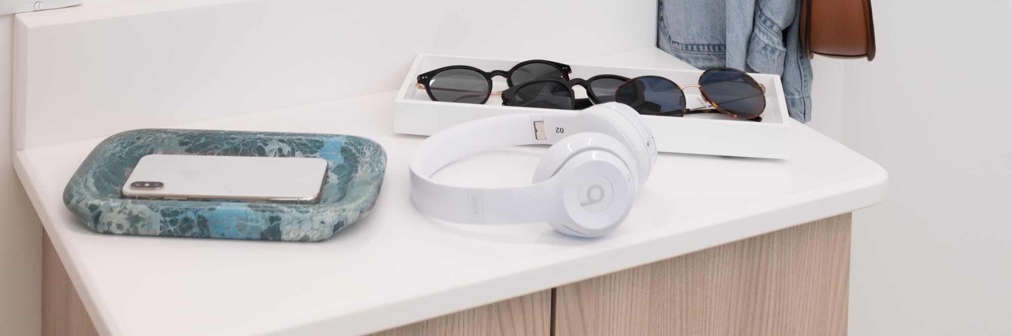 Counter with mirror, headphones, sunglasses and phone holder.