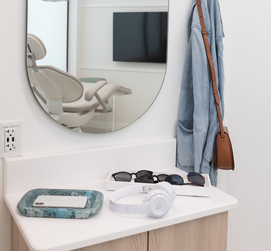 Counter with mirror, headphones, sunglasses and phone holder.