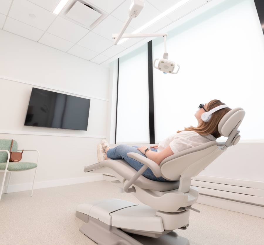 Patient in treatment chair with headphones and sunglasses.