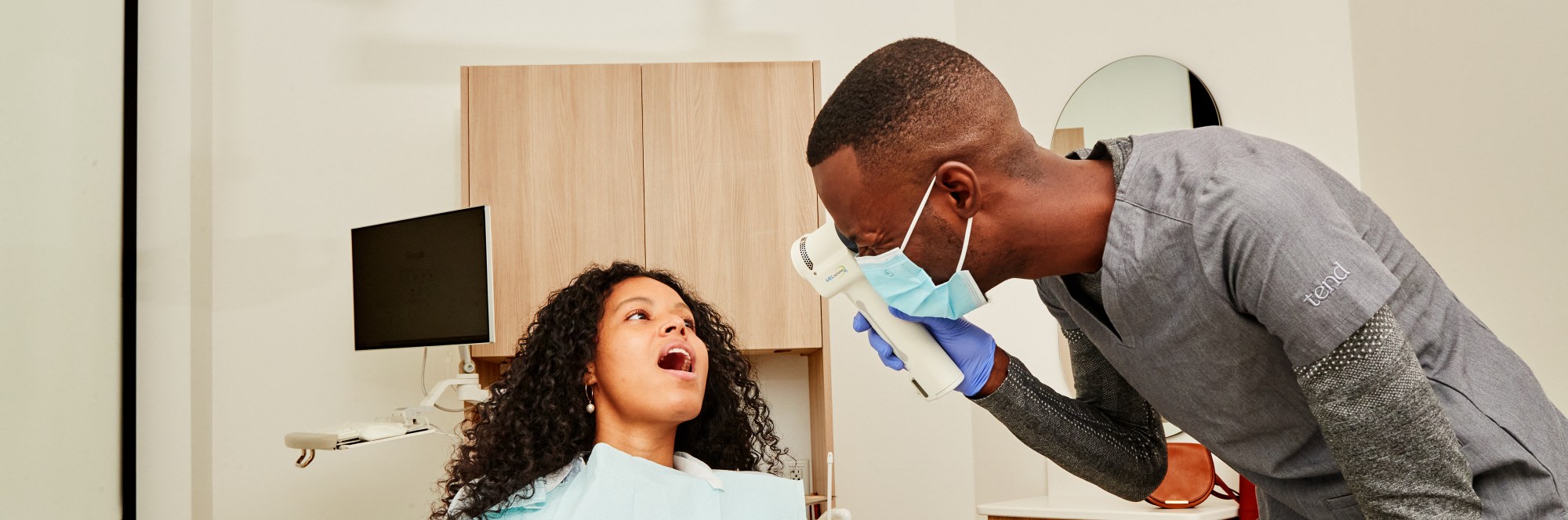 Dental professional using VELscope to exam patient's mouth.