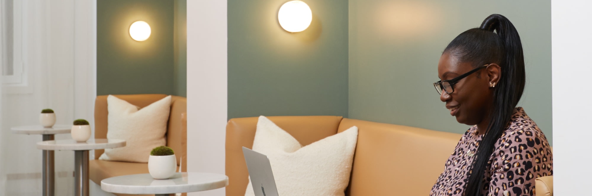 Woman sitting at small table using laptop in dental reception.
