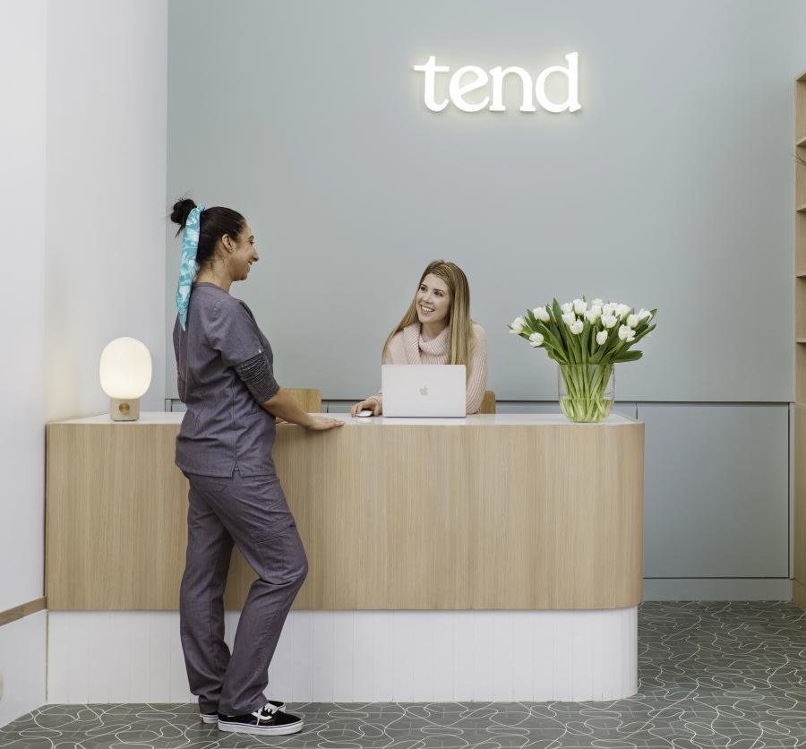 Dental professional and receptionist talking at reception desk.