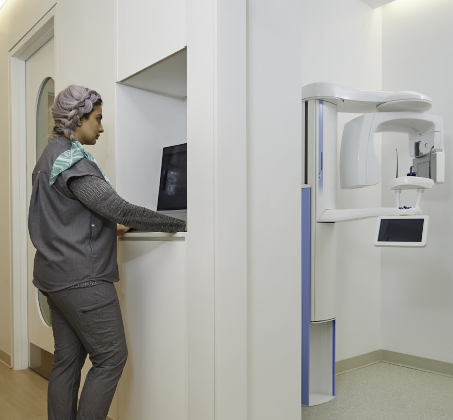 X-ray machine room and dental professional looking at X-ray.