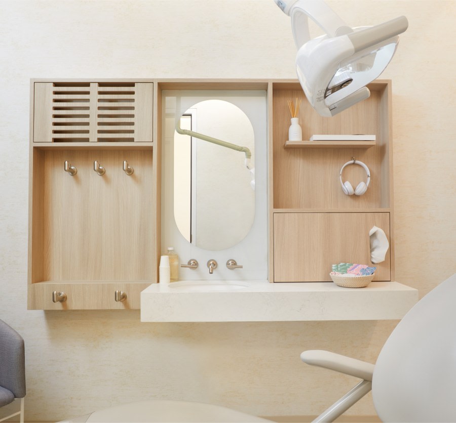 Dental treatment chair with sink, counter and mirror behind it.