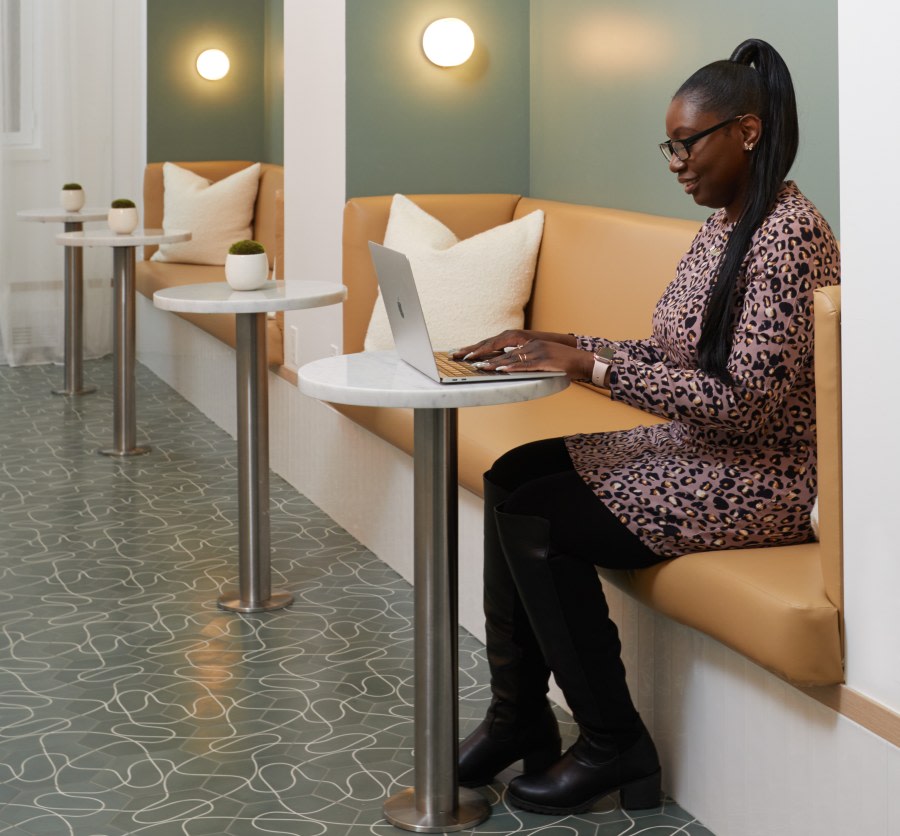 Woman sitting at small table using laptop in dental reception.