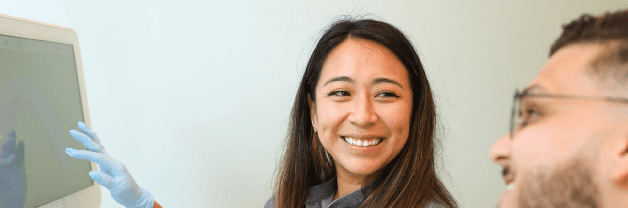 Dental professional pointing and smiling, looking at patient.