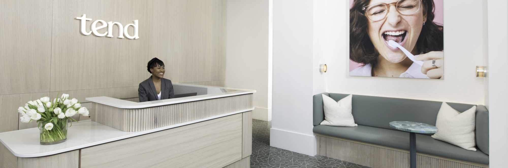 Dental studio reception desk and seating area with green sofa.