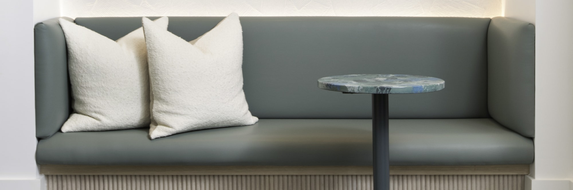 Green sofa with two white cushions and small table.