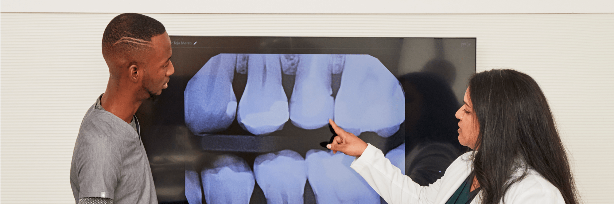 Two dental professionals looking at a large dental X-ray.