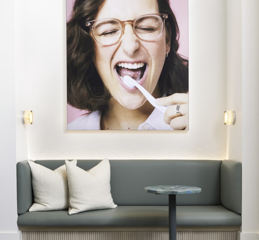 Green sofa with wall art above of a woman brushing her teeth.