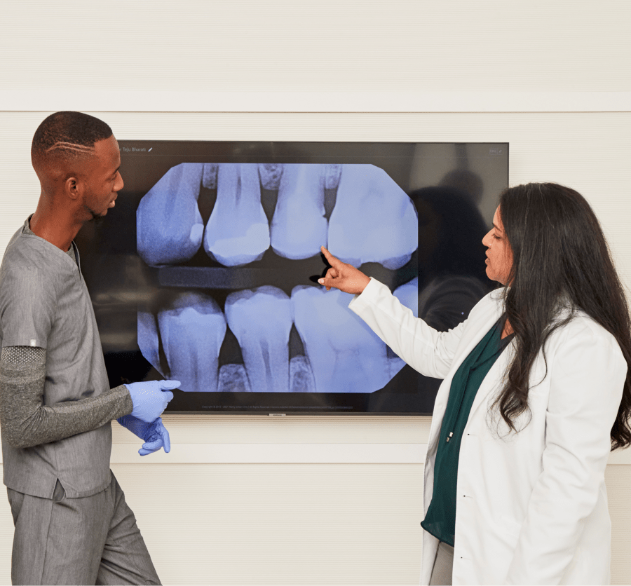 Two dental professionals looking at a large dental X-ray image.