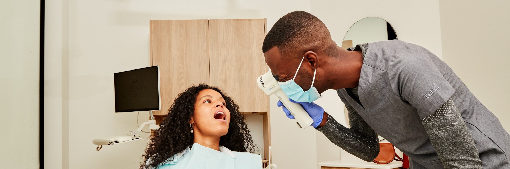 Dental professional examining patients mouth with VELscope.