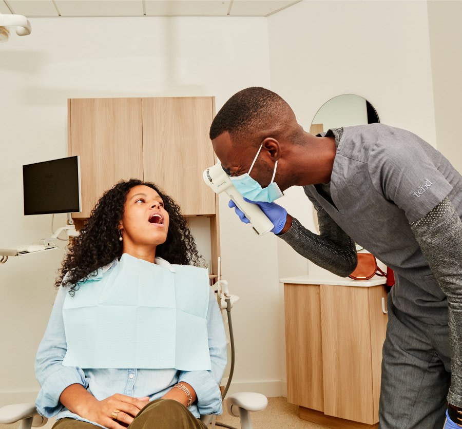Dental professional examining patients mouth with VELscope.