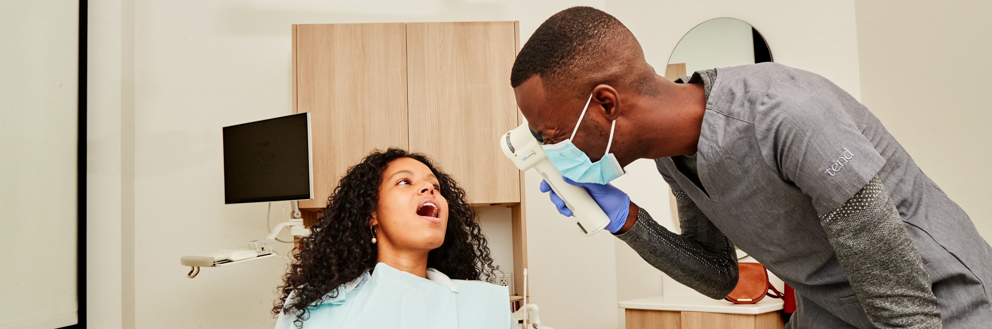 A team member looks at a patient with a VELscope.