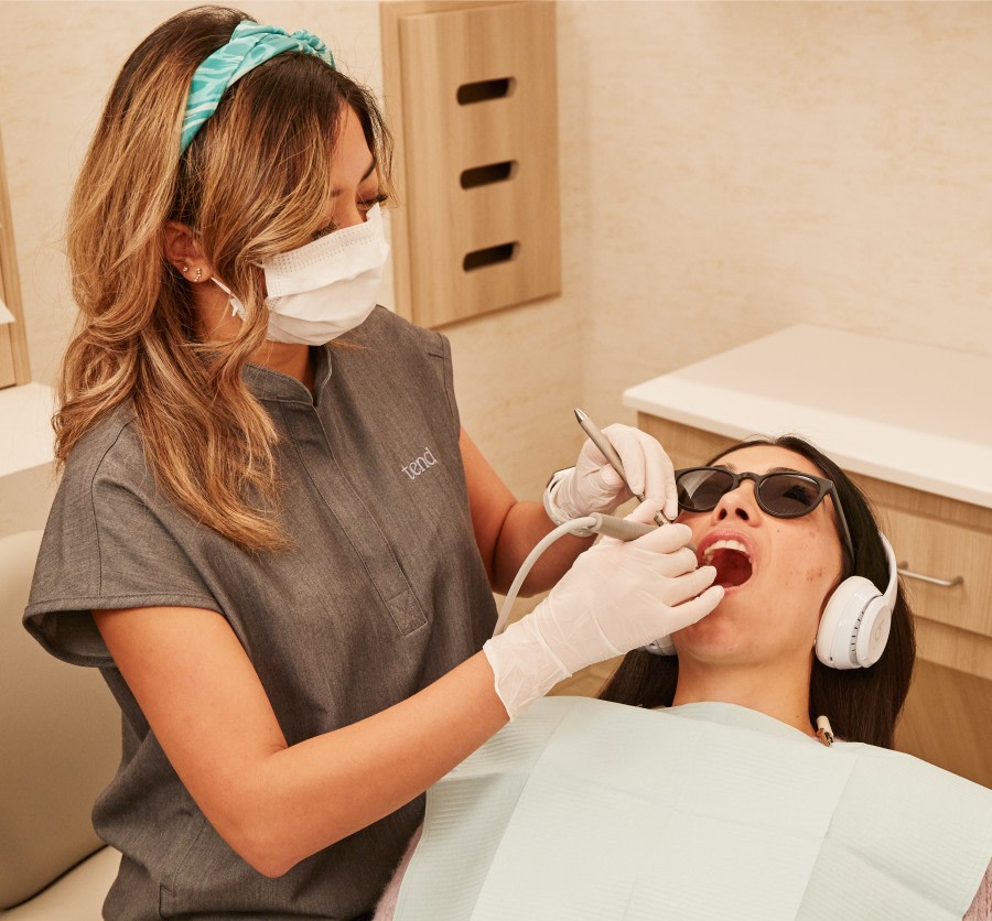 A team member performs a dental exam on a patient.