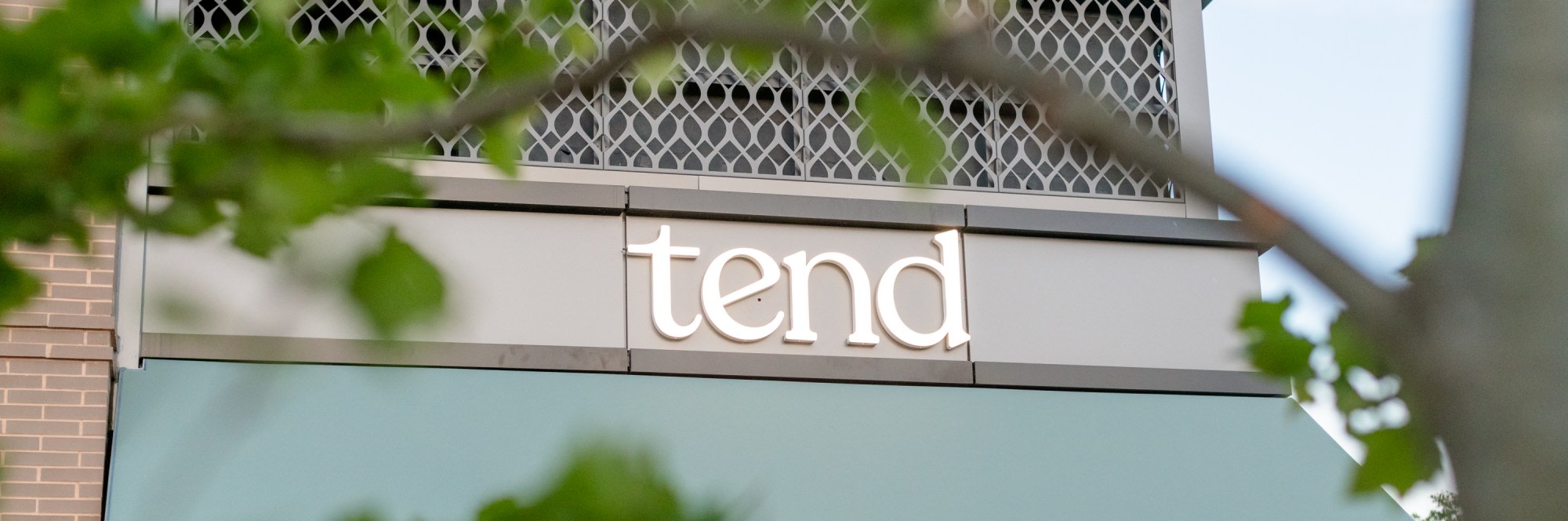 Exterior image of dental studio sign through some tree branches.