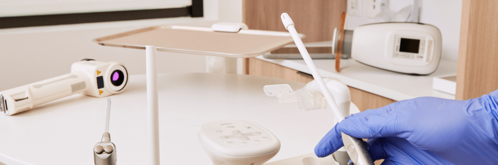 Variety of dental tools with one being held by a gloved hand.