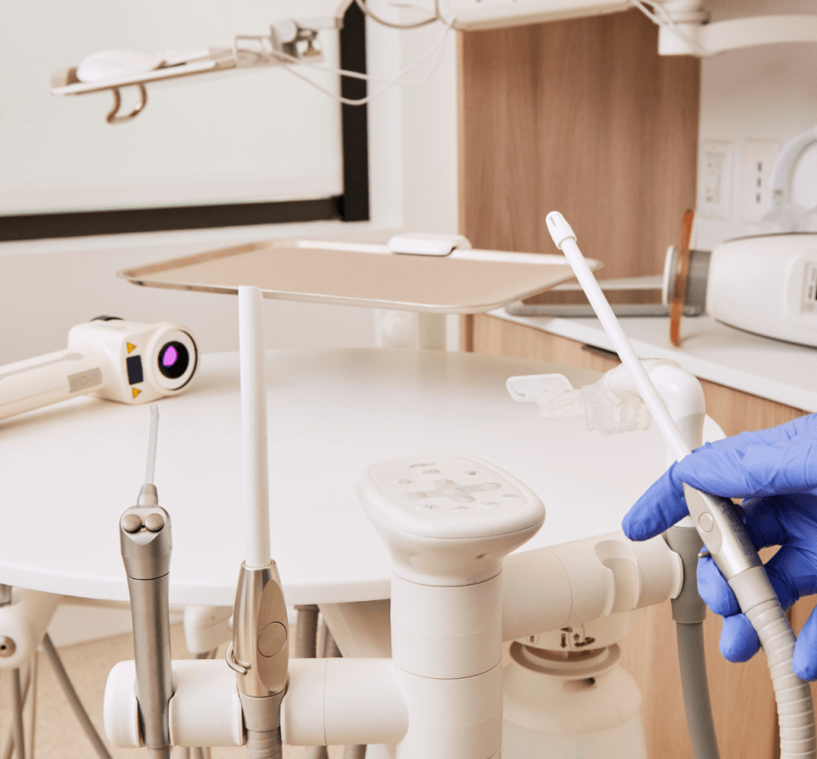 Variety of dental tools with one being held by a gloved hand.