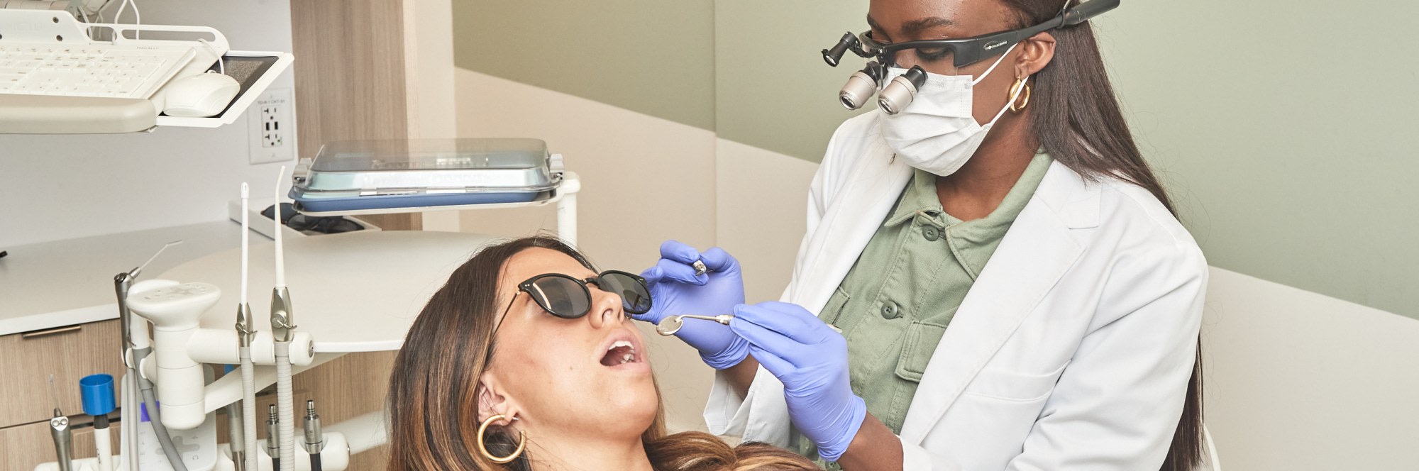 A team member performs a dental exam on a patient.