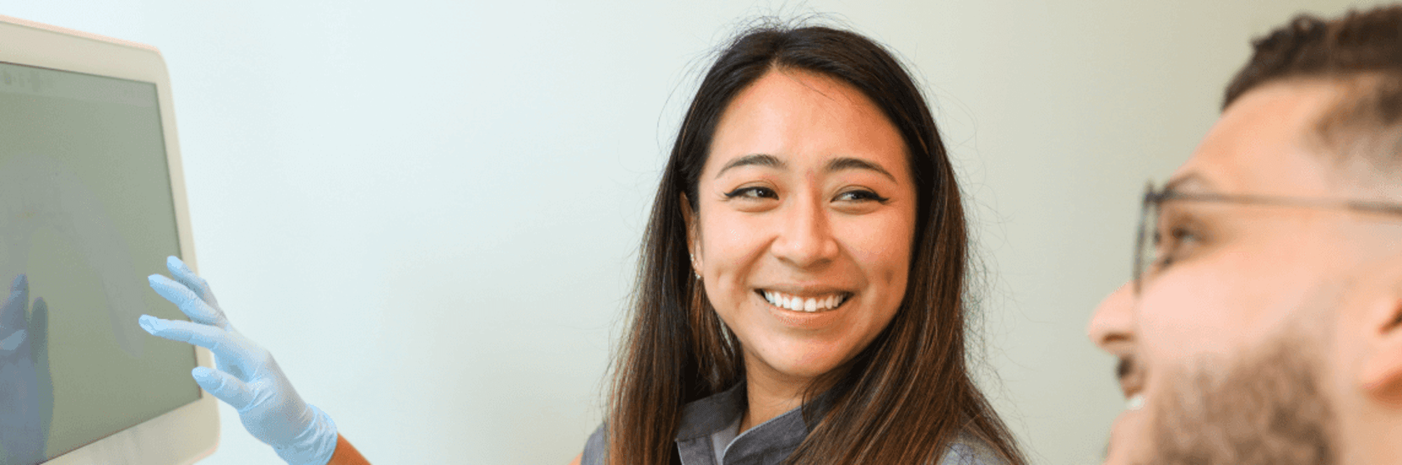 Dental professional smiling and pointing, looking at patient.