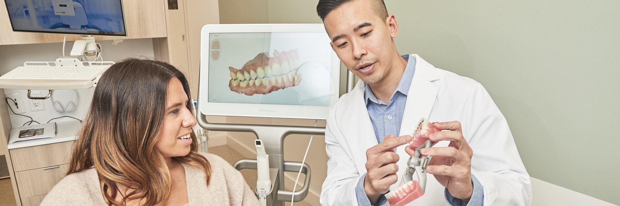 Dental professional showing patient a dental model.