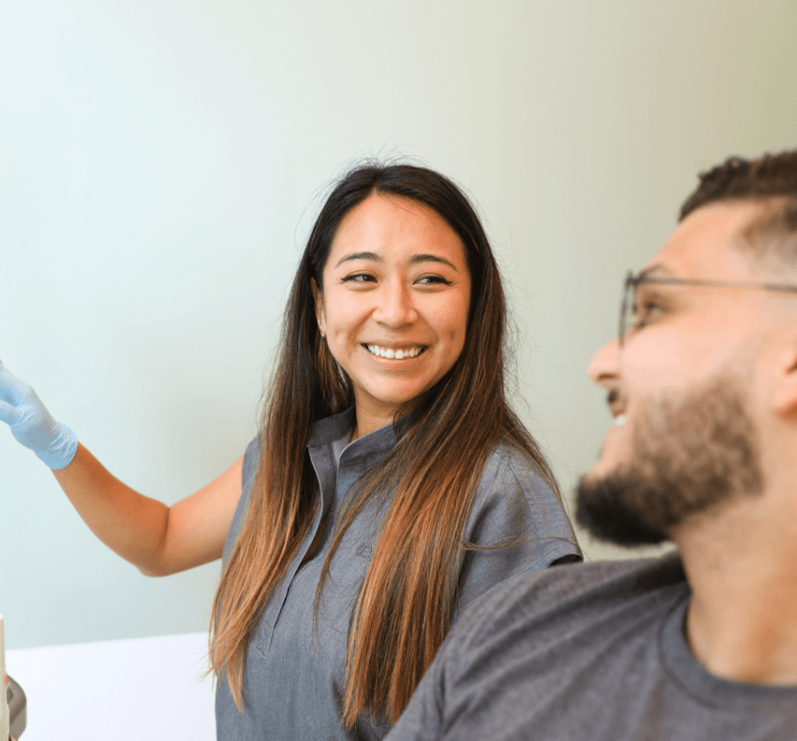 Dental professional smiling and pointing, looking at patient.