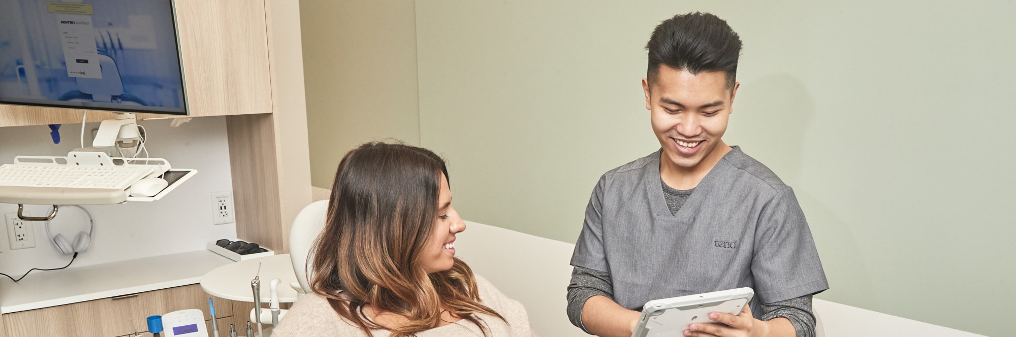 Dental professional looking at tablet while talking to patient.